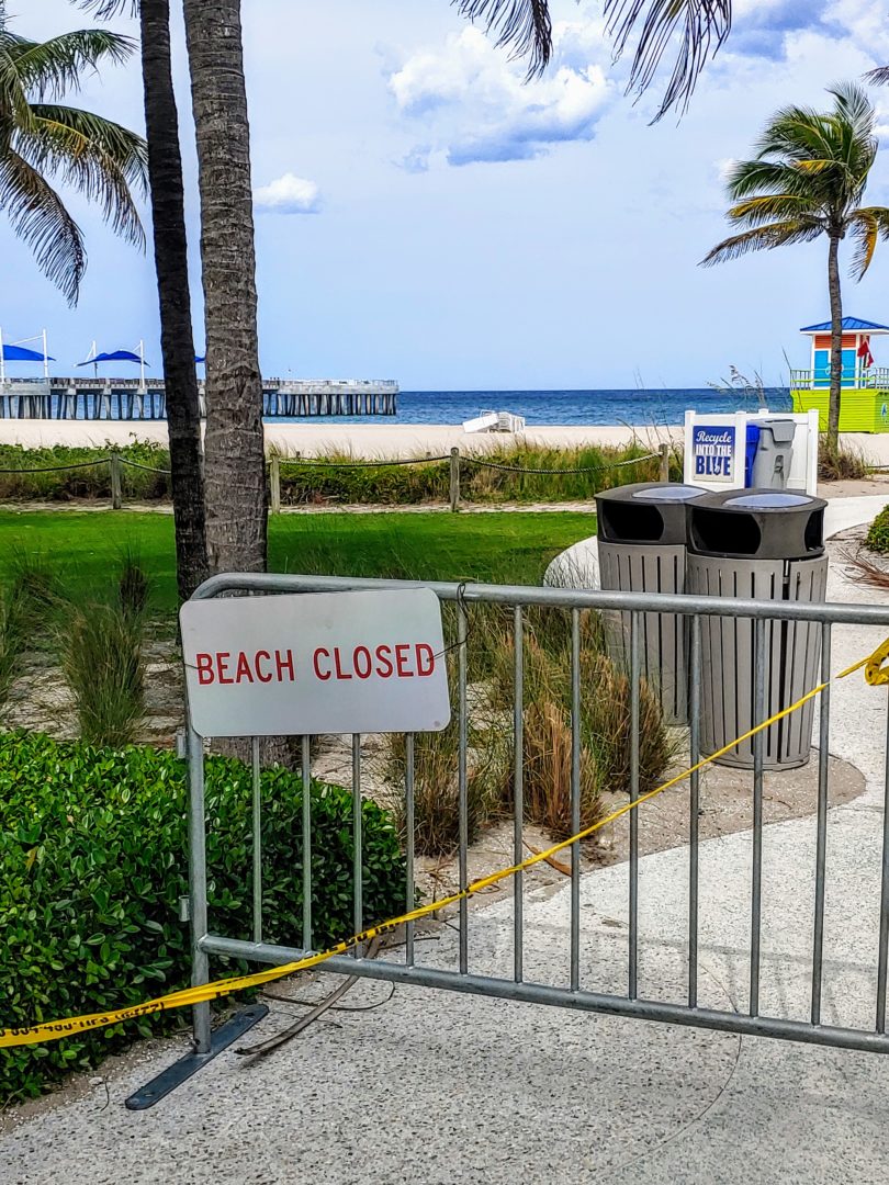 A picture of a gate with a sign that says beach closed on it.