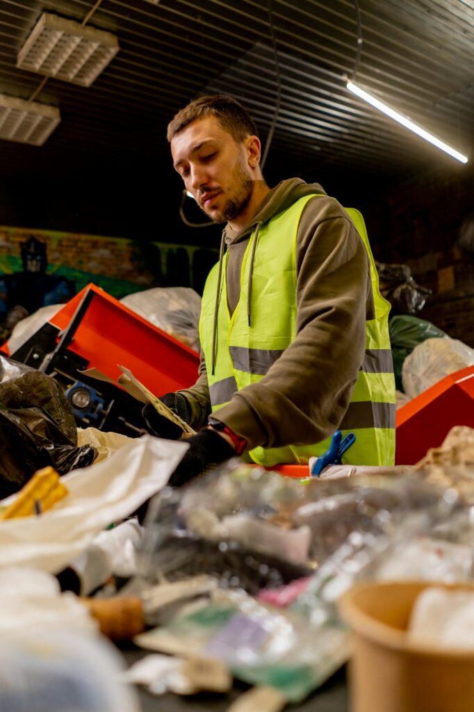 An employee in a uniform at a waste recycling station sorts and sorts garbage on sorting line