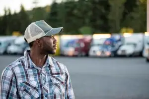 Black man truck driver near his truck parked in a parking lot at a truck stop